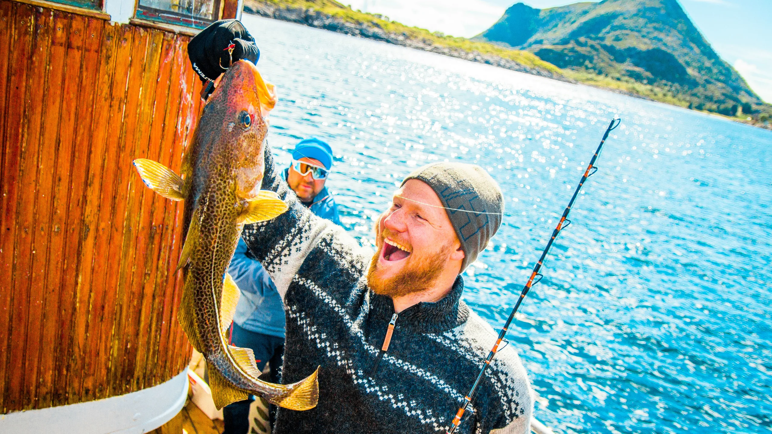 Smiling man holding up a large cod